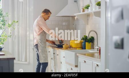 Handsome Young Man Preparing a Healthy Vegetarian Meal on a Frying Pan. Cooking Healthy Green Food in a Modern Kitchen. Natural Clean Diet and Healthy Stock Photo