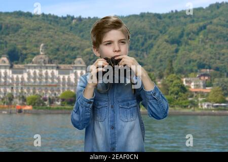 Portrait of thoughtful little boy looking through binoculars. Stock Photo