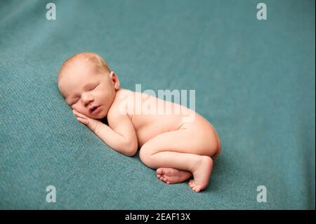 2. Newborn baby boy sleeping at a newborn photoshoot with his hands under his cheeks Stock Photo