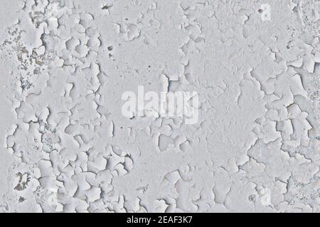 Background of old wall with white peeling paint. Cracked painting of the old surface. Mangy paint with dirty marks on the concrete. Stock Photo