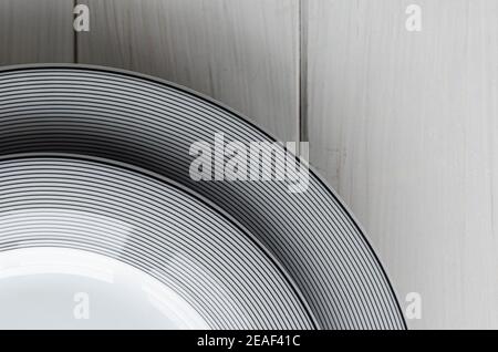 White round classical porcelain plates with a gray pattern stand on a white wooden table Stock Photo