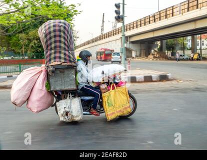 Man on an overladen motorcycle riding through Delhi in India Stock Photo