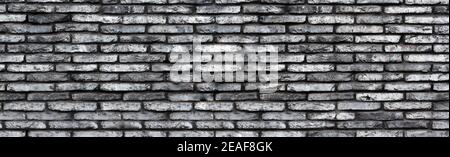 Gray grunge brick wall background. Wide wall texture of rough brickwork for design. Banner Stock Photo