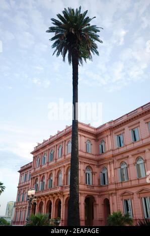 Tall palm tree against Pink House or Casa Rosada building is a mansion and office of President of Argentina located on Plaza De Mayo. Buenos Aires, Ar Stock Photo