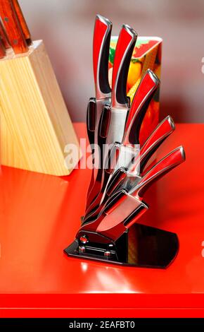 A set of beautiful stainless steel metal kitchen knives in a black elegant case on a red background. Stock Photo