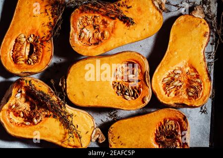 Roasted pumpkins with thyme herbs on baking sheet, top view, plant based food Stock Photo