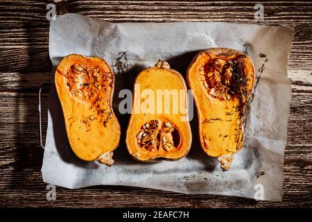 Roasted pumpkins with thyme herbs on baking sheet, top view, plant based food Stock Photo