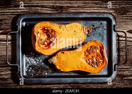 Roasted pumpkins with thyme herbs on baking sheet, top view, plant based food Stock Photo