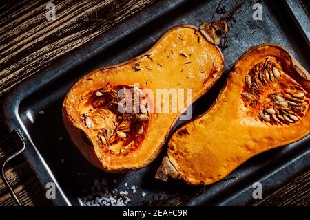 Roasted pumpkins with thyme herbs on baking sheet, top view, plant based food Stock Photo