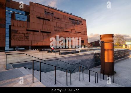 Gdansk, Poland - 05.06.2017: Young couple on a bench in front of modern industrial building. European solidarity centre, Gdansk, Poland. Solidarnosc Stock Photo