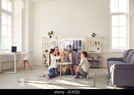 Happy family father mother and two children sitting on floor and playing at home Stock Photo