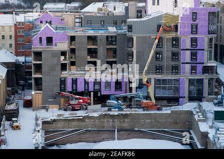 Workmen on a cherry picker installing cladding panels to a new luxury apartment block in Edinburgh city centre. Stock Photo