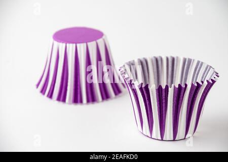 Close-up of two purple striped paper muffin cups, selective focus, on white background, horizontal Stock Photo