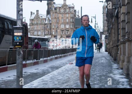 A man running in Edinburgh city center after an early morning snowfall Stock Photo
