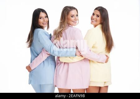 Three women in pastel suits posing over white background Stock Photo