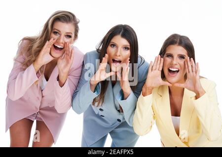 Three women in pastel suits posing over white background Stock Photo