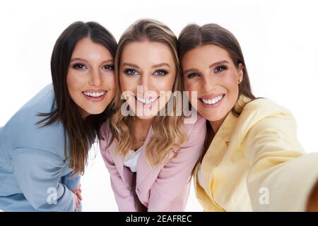 Three women in pastel suits posing over white background Stock Photo