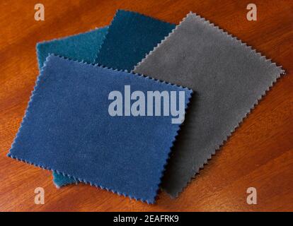 Four velvet fabric samples in shades of blue green on wooden table Stock Photo