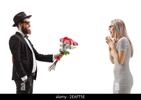 Bearded man in a suit giving a bouquet of red roses to a surprised woman isolated on white background Stock Photo