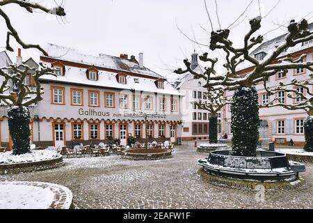 Heidelberg, Germany - February 2020: Town square called 'Karlsplatz' with empty restaurant and snow in winter in historic city center of Heidelberg Stock Photo