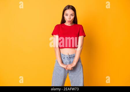 Young girl sending flirty air kisses wear red crop top jeans isolated over bright yellow color background Stock Photo