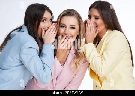Three women in pastel suits posing over white background Stock Photo