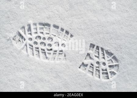 Clearly defined footprint / imprint in fresh snow of rubber lug sole with deep indentations from mountaineering boot / hiking boot in winter Stock Photo