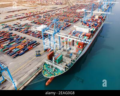 Container ship being loaded and unloaded at terminal freight port, international shipping and global commerce, modern cargo harbor and yard for mariti Stock Photo