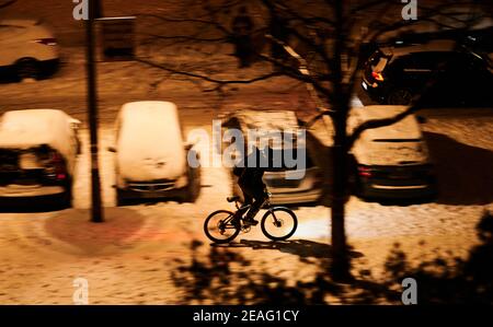 Berlin, Germany. 09th Feb, 2021. A cyclist rides by lantern light on the snow-covered sidewalk. Credit: Annette Riedl/dpa/Alamy Live News