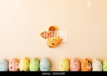 Row from multicolored eggs on the pastel background.Funny egg like a bumblebee with paper wings.Easter concept,creative layout.Funny greeting card wit Stock Photo