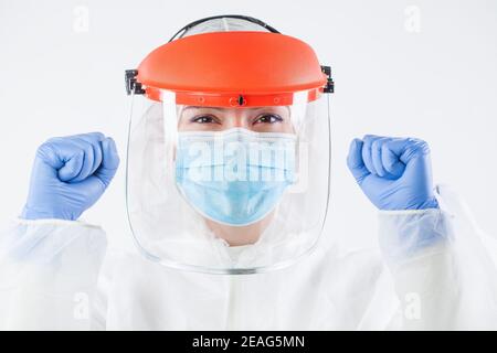 Healthcare professional in personal protective equipment, wearing surgical gloves, face shield, white protective hazmat biohazard suit, clenched fists Stock Photo