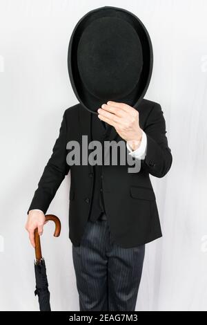 Portrait of Man in Dark Suit Tipping Bowler Hat Politely. Classic and Eccentric English Gentleman. British Businessman. Stock Photo