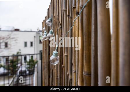 LED mint color light bulbs with wires hanging on a bamboo screen wall outside on a deck Stock Photo