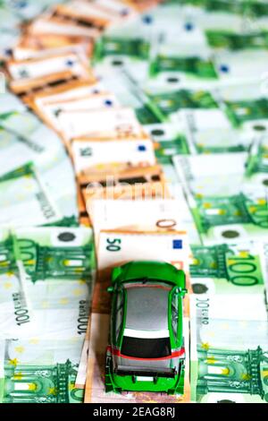 Toy car on a path made up of fifty euro bills bordered by green hundred euro bills. Stock Photo