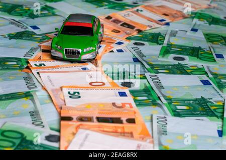 Toy car on a path made up of fifty euro bills bordered by green hundred euro bills. Stock Photo