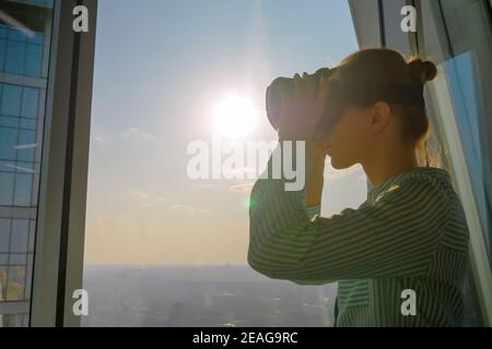 Young woman using virtual reality headset against skyscraper window - VR concept Stock Photo