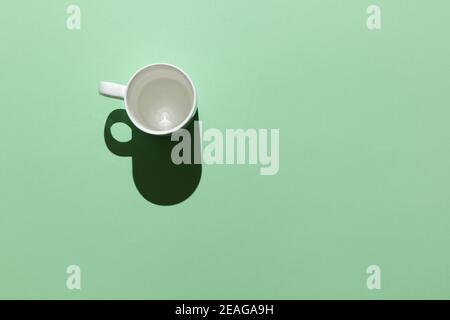 Blank white mug in hard light on a pastel green background, top view, flat lay. Mockup for design, you can insert a photo of a hot drink, coffee, tea, Stock Photo