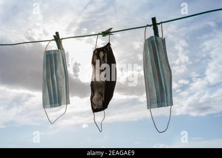 Face masks hanging on a rope with the sky in background. Coronavirus epidemic (COVID-19) concept Stock Photo