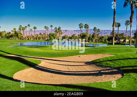 golf course hole, surrounded by lakes, palm trees and mountains Stock Photo