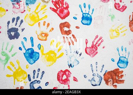 White wall with colorful multicolored hand prints. Stock Photo