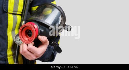 Full protective breathing mask in hand of unrecognized firefighter Stock Photo