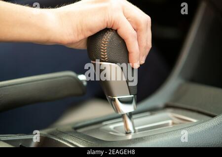 Close up of woman driver holding her hand on automatic gear shift stick driving as car. Stock Photo