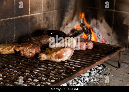 Barbecue. Meat cuts of cow, chicken and pork warming on the embers on an iron grill. Traditional Argentinian bbq. Argentina meal. Stock Photo