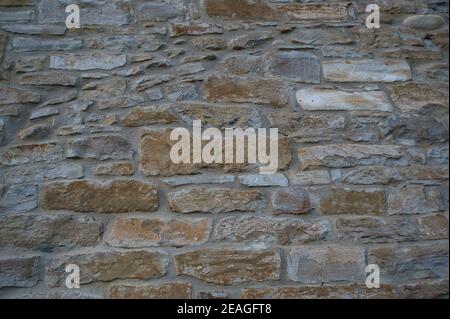 Stone wall of natural stones in different sizes; Rustic stone veneer in shades of brown and beige; Stock Photo
