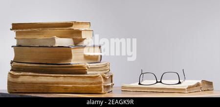 stack of old books and reading glasses lie on the table Stock Photo
