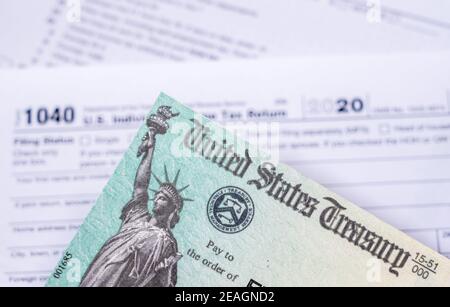 US Treasury stimulus check laying on a form 1040 tax return for 2020 to illustrate questions about qualification for payment Stock Photo