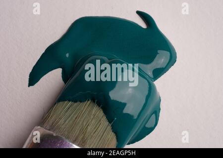 Paint brush applies tidewater green paint to the paper, close-up Stock Photo