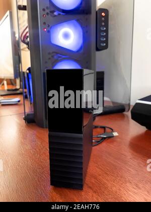 Close up of an external USB hard drive with desk top and computer in background Stock Photo