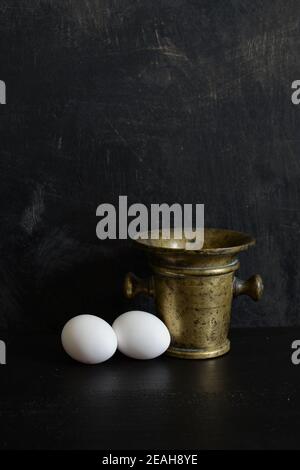 Antique brass Mortar and two white eggs Stock Photo