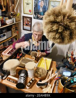 08 February 2021, Saxony-Anhalt, Naumburg: In her small brush manufactory, which also serves as a salesroom, 81-year-old brush maker Ursula Römer works on a feather duster with horsehair bristles. Although her shop is closed due to the pandemic, a lot of orders are currently coming in by phone or in writing from all over Germany for large and small brooms, spider sweeps, feather dusters or even wall and ceiling brooms. In her traditional shop, which her great-grandfather opened in 1885, the 81-year-old makes her brushes and brooms with a wide variety of bristles in the old, traditional way usi Stock Photo